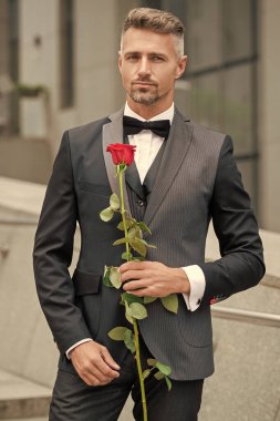 Siyah smokinli zarif bir adam. Smokin papyon takan adam dışarıda. Kırmızı güllü yakışıklı smokinli adam..