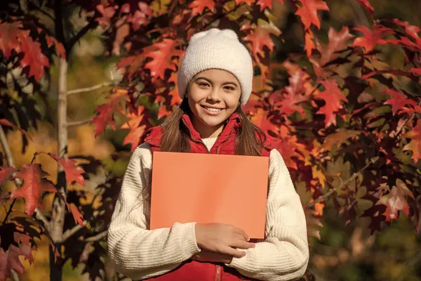stock image teen girl make an offer. girl offering advertisement in autumn nature. fall seasonal discount. offering autumn tips. school time in fall. best offer for this season. autumn offer sale.