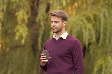 Genç yakışıklı adam sabah kahvesini dışarıda içiyor..