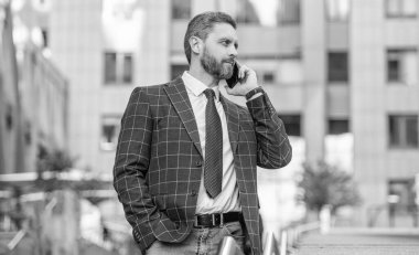 Kendine güvenen iş adamının dışarıda telefon görüşmesi var. İş adamının sokakta telefon görüşmesi yapması. İş adamı dışarıda telefon ediyor. İş adamının telefondaki fotoğrafı ve konuşması..