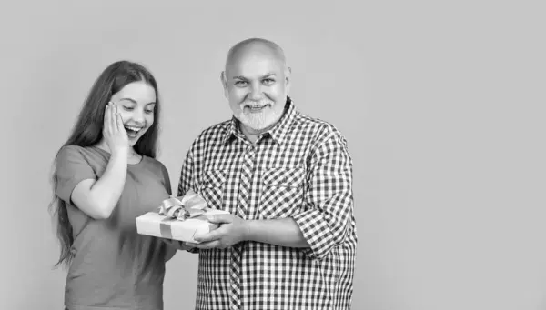 Stock image amazed teen girl and grandfather with present box for anniversary.