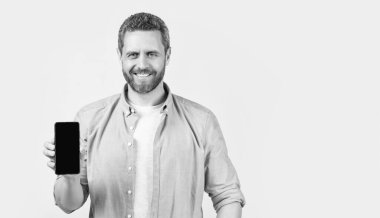 Stüdyonun arka planında izole edilmiş bir telefon uygulaması gösteren memnun adam. Adam stüdyoda telefon uygulaması gösteriyor. Telefon uygulaması gösteriliyor. Telefon uygulaması gösteren adamın fotoğrafı.