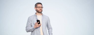 Gözlüklü adam akıllı telefondan fotokopi odasıyla sohbet ediyor. Adam telefonda mesajlaşıyordu. Akıllı telefon iletişimi. Adam gökyüzü arka planında sohbet ediyor.