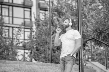 image of man in music headphones with coffee. man in music headphones outdoor. man in music headphones in the street. man in music headphones outside.