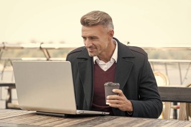 Formalite blogunda mutlu adam blogcu. Laptopta iş blogu. Açık kafede kahve içiyor..