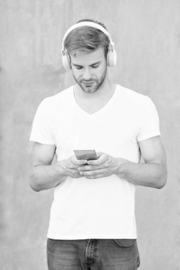 Yakışıklı adam mp3 müzik listesini beyaz gömlekle seçiyor. İnsan mp3 müzik listesinin kulaklıkla fotoğrafı. Adam mp3 müzik listesini açıyor. Adam dışarıda mp3 müzik listesi kullanıyor.