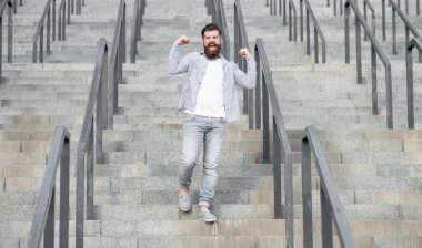 shouting bearded guy walk downstairs. full length of guy with beard. hipster guy outdoor at stairs.