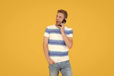 Telefonla konuşan şaşırmış bir adam. Telefondaki adam sarıda izole bir şekilde konuşuyor. Adam stüdyoda telefonla görüşüyor. Adam ailesi ve arkadaşlarıyla konuşmak için telefonunu kullanıyor..