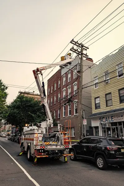 stock image Jersey City, USA - June 30, 2023: Linemen on repair works from a power line bucket truck.