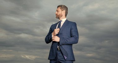 Dışarıdaki takım elbiseli adamın fotoğrafı. Gökyüzü arka planındaki takım elbiseli adam. Dışarıdaki takım elbiseli adam. Takım elbiseli adam..