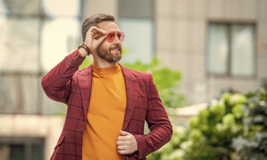 Sokaktaki erkek giyim sektöründe karizmatik bir adam. Dışarıda erkek giysili bir adam var. Ceketli bir adamın fotoğrafı. Erkek giyim mağazasındaki adam..