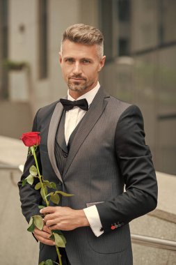 Siyah smokinli zarif adam. Smokinli papyonlu adam dışarıda. Kırmızı güllü yakışıklı smokinli adam..