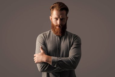 Gri arka planda sakallı ve bıyıklı traşsız bir adam. Traşsız adamın stüdyo çekimi. Bıyık ve sakal bakımı. Tıraşsız yakışıklı adamın sakalı ve bıyığı var..