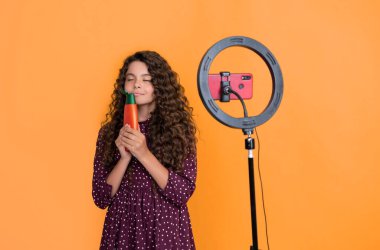 Uzun kıvırcık saçlı çocuk blog kokusu şampuanı için video yapıyor.