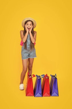 Sarı arka planda alışveriş torbaları olan genç bir kız. Boşluğu kopyala.