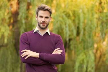 Gündelik tarzda giyinen yakışıklı genç adam dışarıda ellerini çapraz yaptı. Boşluğu kopyala.