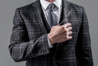 Berber adamın yakın plan çekimi gri arka planda izole edilmiş bir makas tutuyor. Makasla berber adam. Berber salonundaki makaslı adam. Berber makaslı bir adamın fotoğrafı..