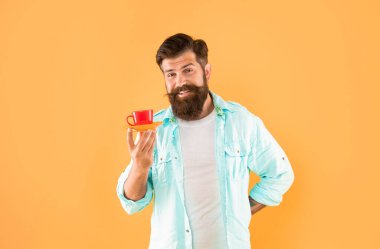 Sarı arka planda kahveli, gömlekli neşeli, tıraşsız bir adam..