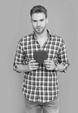 Aşkın kalbini tutan adam gri arka planda izole edilmiş bir hediye. Kalbi olan bir adamın stüdyo fotoğrafı. Sevgililer günü ve aşk. Sevgililer Günü için bir erkeğin kalp aşkı hediyesi..