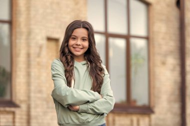 Kendine güvenen genç kız rahat kapüşonlu mutlu kollarını açık havada çapraz tutuyor..