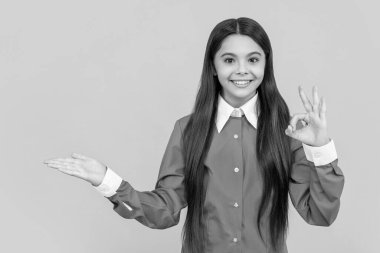 Ürün sunmak ve sunmak. Üniformalı genç kız reklam yapıyor. Genç kız ürünleri fotokopi alanıyla sunuyor. Kız iyi bir hareket gösteriyor. Genç öğrencinin mutlu bir yüzü var. Anlık satış.