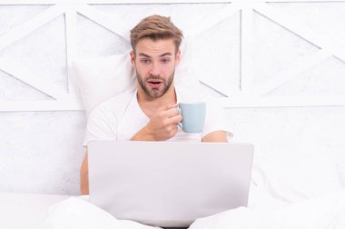 Adam yatakta yatıp dizüstü bilgisayarla internette sörf yapıyor. Bilgisayarda evden çalış. Hafta sonu işkolik. Sabah kahvesi hazır. Yatakta serbest çalışan. Milenyum adamı evde dizüstü bilgisayarda çalışıyor. Video çağrısı.