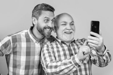 Mutlu bir neslin fotoğrafı telefonda video çekiyor. Nesiller boyu erkekler sarıda izole videolar çeker. Nesiller boyunca erkekler stüdyoda video çeker. jenerasyon erkekleri arka planda video yapıyor.