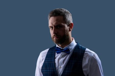 Yakışıklı, karizmatik garson smokin giyer, şık papyon giyer ve gri renkte klasik üniforma giyer..