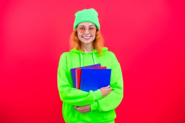 Üniversitede ya da üniversitede ders kitabı okuyan genç bir kız pembe üzerine izole edilmiş..