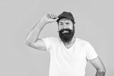 Arka planda şaşkın bir kurye var. Teslimatçı kurye stüdyoda. Teslimatçı kuryenin şapkalı fotoğrafı. Teslimatçı kurye sarıda izole edilmiş..