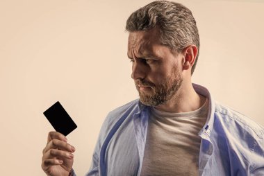 upset guy with business debit in studio. guy holding business debit. photo of guy hold business debit. guy show business debit isolated on studio background.