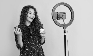 glad kid with long curly hair making video for blog hold powder brush.