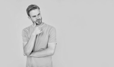 pondering unshaven young man in blue shirt on yellow background, lifestyle.