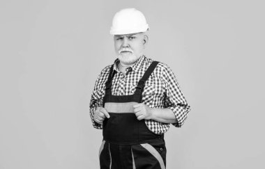 Sarı arka planda miğferli kıdemli bir inşaatçı..