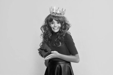 Sarı arka planda mevcut kutusuyla taç giymiş mutlu bir kız..