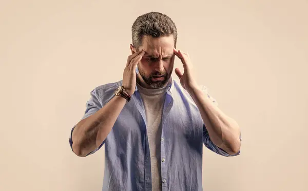 stock image mature man suffer from headache and migraine in studio. photo of man with migraine headache. man with headache or migraine wear shirt. man with headache or migraine isolated on grey background.