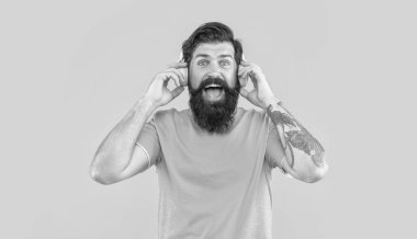 Şaşkın DJ 'in kulaklıklarıyla müzik. Kulaklıklı adam sarı arka planda izole edilmiş. Stüdyoda müzik kulaklığı takan DJ. Adam DJ kulaklıklarıyla müzik dinliyor..