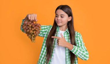 happy child with grapes fruit on yellow background. diet.