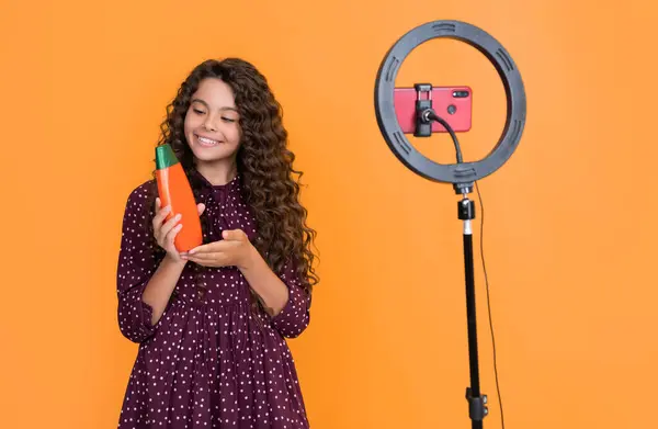 stock image happy kid with long curly hair making video for blog hold shampoo.