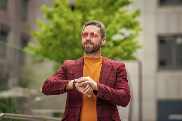 stock image punctual man check time in the street. punctual man check time outside. photo of punctual man check time on watch. punctual man in jacket check time outdoor.