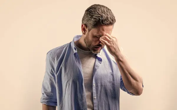 stock image man with headache or migraine isolated on grey. mature man with headache and migraine in studio. photo of man with migraine headache. man with headache or migraine wear shirt.