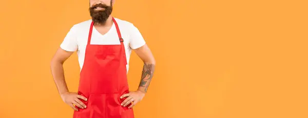 stock image Happy man crop view in red apron keeping arms akimbo yellow background copy space, householding.