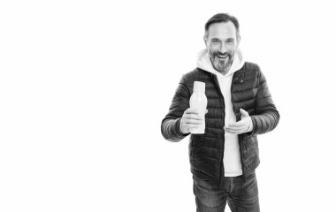 Beyaz arka planda izole edilmiş su şişesi sunan kır saçlı adam. Olgun bir adam stüdyoda su şişesini sunuyor. Şişe boz adamın elinde. Su şişesi, olgun adam sunar..