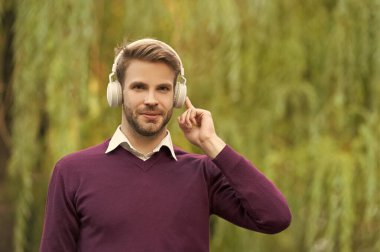 smiling young handsome man listen music in headphones outdoor.