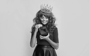 Gülümseyen kraliçe tacı ve sarı arka planda mevcut kutu..