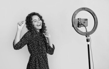 Mutlu çocuk uzun kıvırcık saçlarıyla blogda video çekerken iyi eğlenceler..