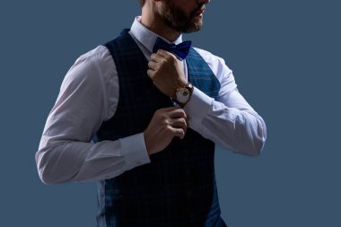 Pahalı bir kol saati. Papyonlu adam ve saat. Zarif saat aksesuarı. Zaman doldu. Gri renkte soyutlanmış zarif bir beyefendi. Erkek aksesuarı. Papyonlu beyefendi lüks saat gösteriyor. Hazırlanıyor..