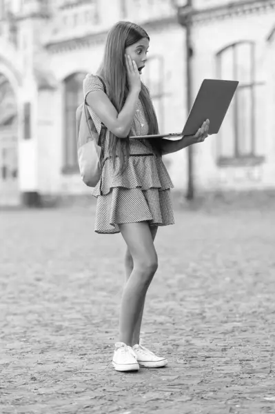 stock image amazed school girl stydy online. school girl stydy online with computer. school girl stydy online outdoor. photo of school girl stydy online.