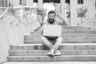 Hüsrana uğramış bir adam cep telefonuyla konuşuyor. Dizüstü bilgisayardaki bahis sonuçlarını kontrol ediyor. Bahisçi kaybeden. Cep telefonu ve laptop bahisleri. Kumarbaz ezik. Cep telefonu kullanarak online bahis.