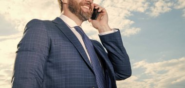 Kesilmiş adamın fotoğrafı telefonda konuşuluyor. Adamın gökyüzü geçmişinde telefon konuşmaları var. Adam dışarıda telefonla konuşuyor. Adamın telefonda konuşma kıyafeti var..